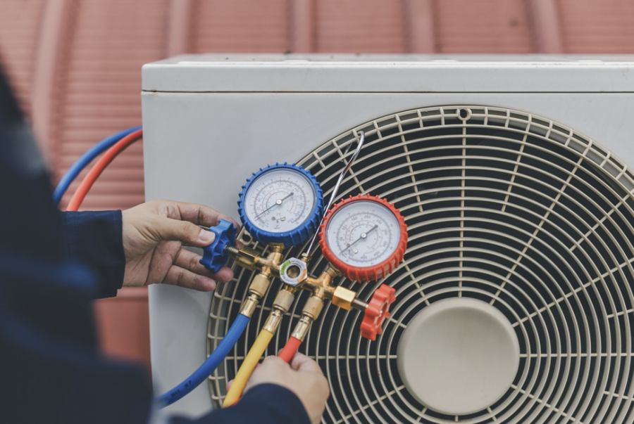 HVAC contractor connecting manifold gauges to outdoor air conditioner unit